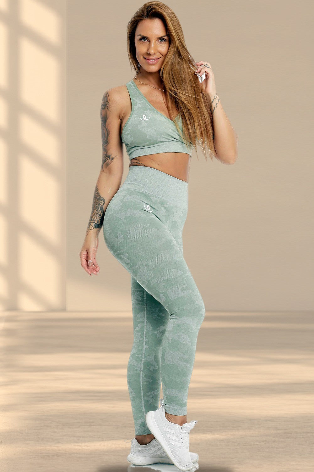 Le mannequin se tient debout dans le haut vert menthe et un legging à imprimé camouflage, avec des chaussures blanches.