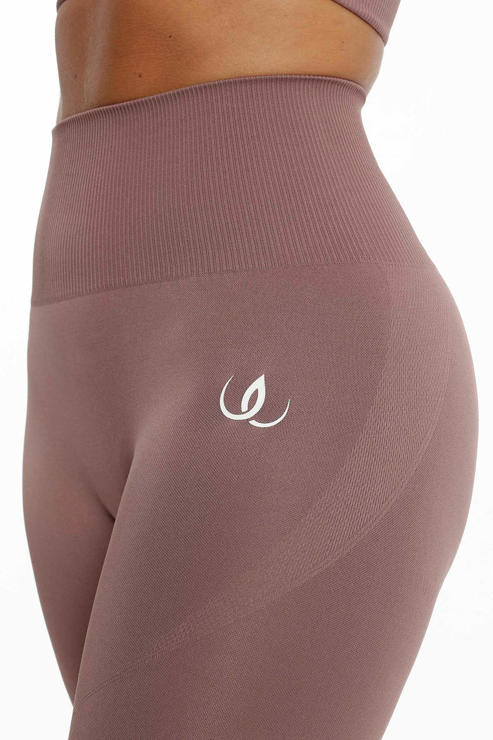 Der gerippte Bund und das weiße Logo an der Hüfte, der Stoff in einem gedeckten Rosébraun.