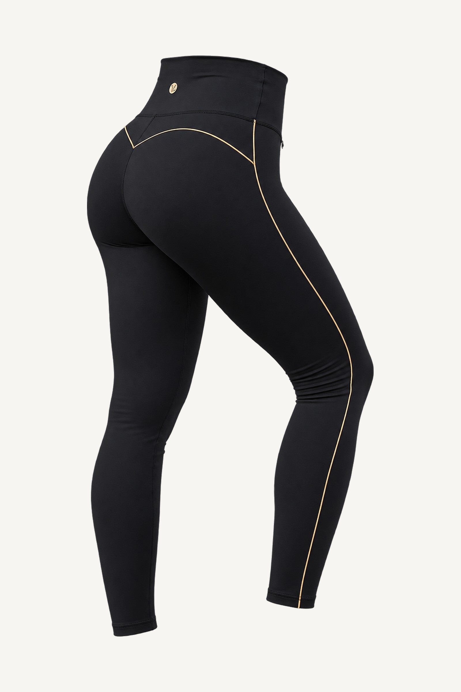 Slimline FlexFlow Träningstights Svart/Guld freigestellt, schräg von hinten. Eine einzige Goldlinie am Bein entlang und ein goldfarbenes Plättchen an der Taille.