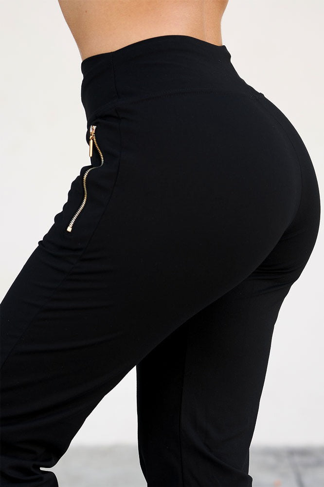 La hanche avec une large ceinture et une fermeture éclair dorée qui descend vers la poche du pantalon.