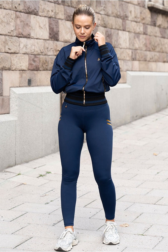In città la modella indossa i leggings navy e una giacca nella stessa tonalità con zip color oro.