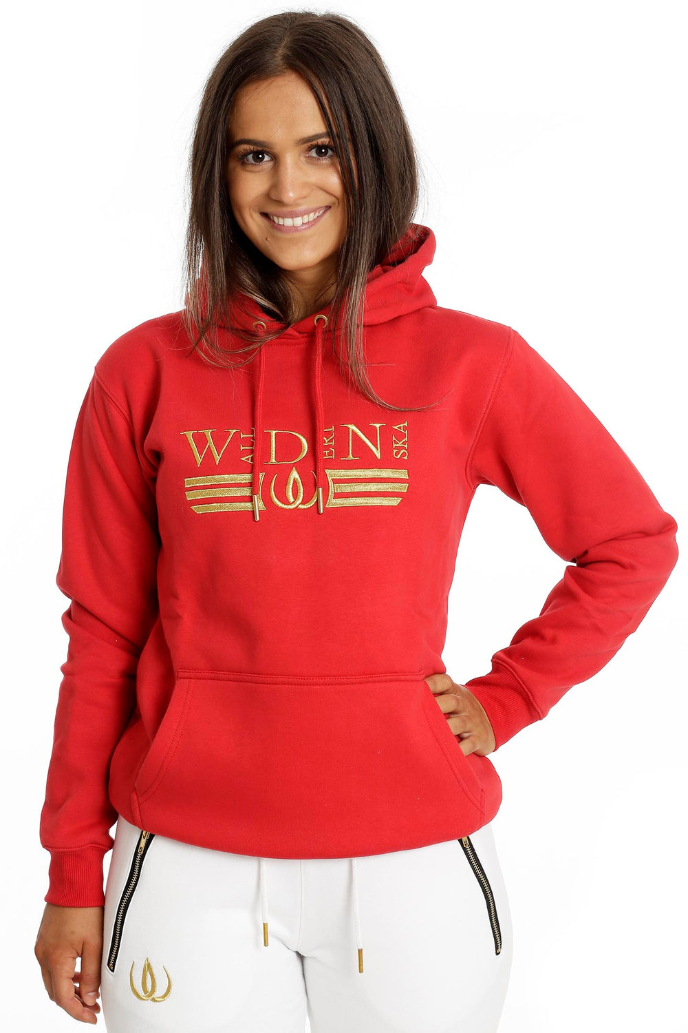 Das Model trägt den roten Hoodie mit Goldstickerei und Kängurutasche zu Deluxe Joggers Weiß.