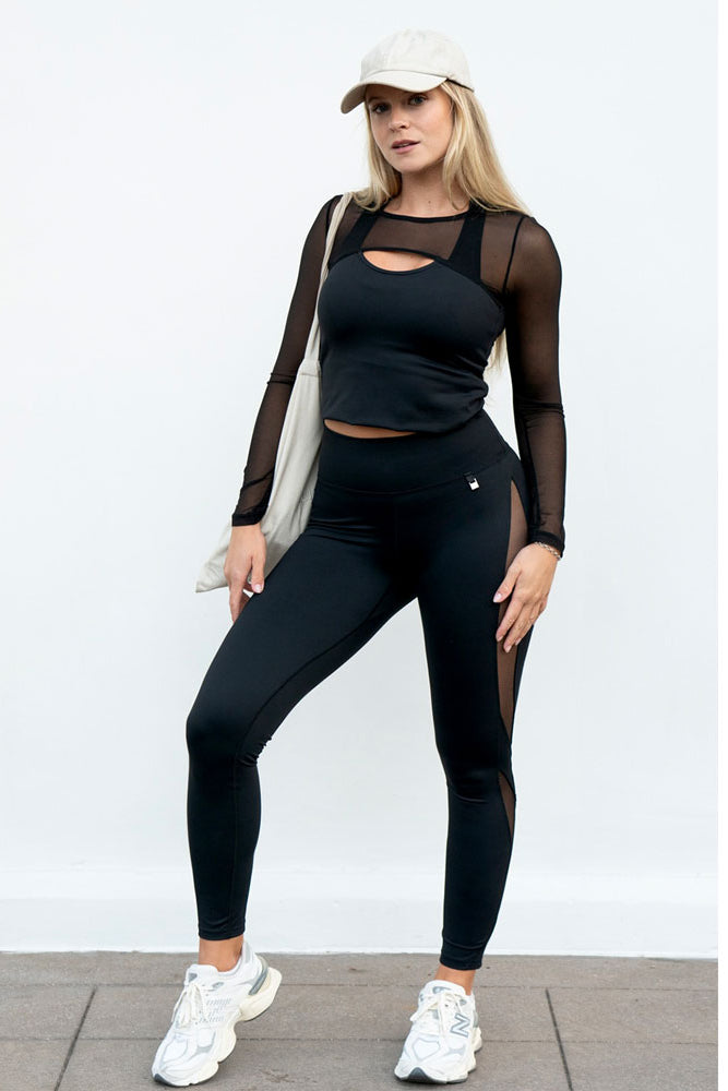 Zur Leggings werden ein schwarzes Top mit Meshärmeln, eine Cap und ein weißer Stoffbeutel getragen.