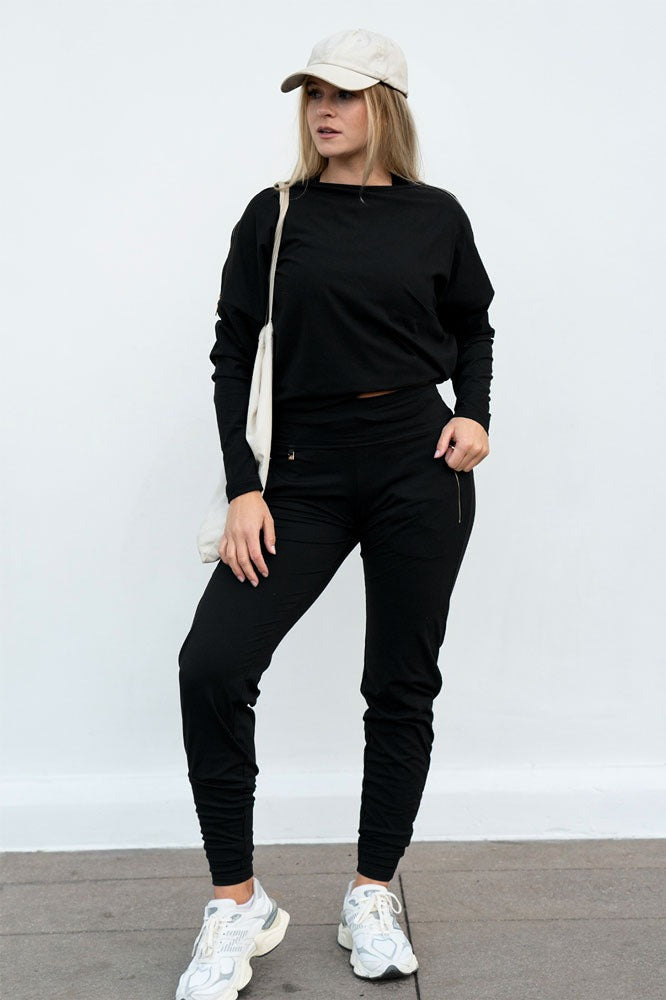 Manches amples et bas droit sur le pull, porté avec un pantalon, une casquette et un tote bag blanc.