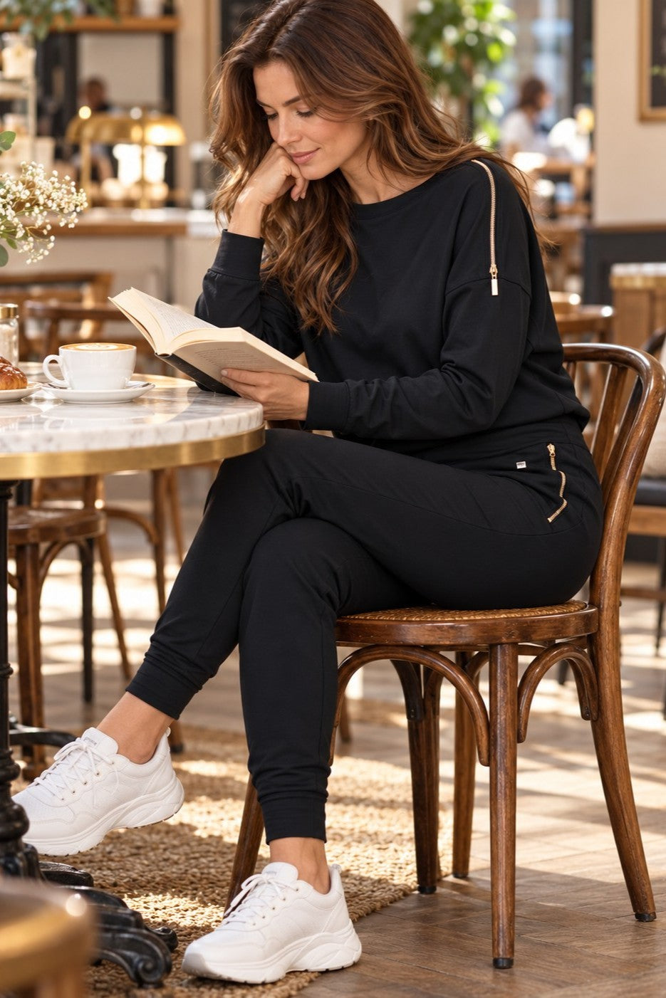 Edge Casual Zip-setet i svart på ett café, med en bok och en kopp kaffe.