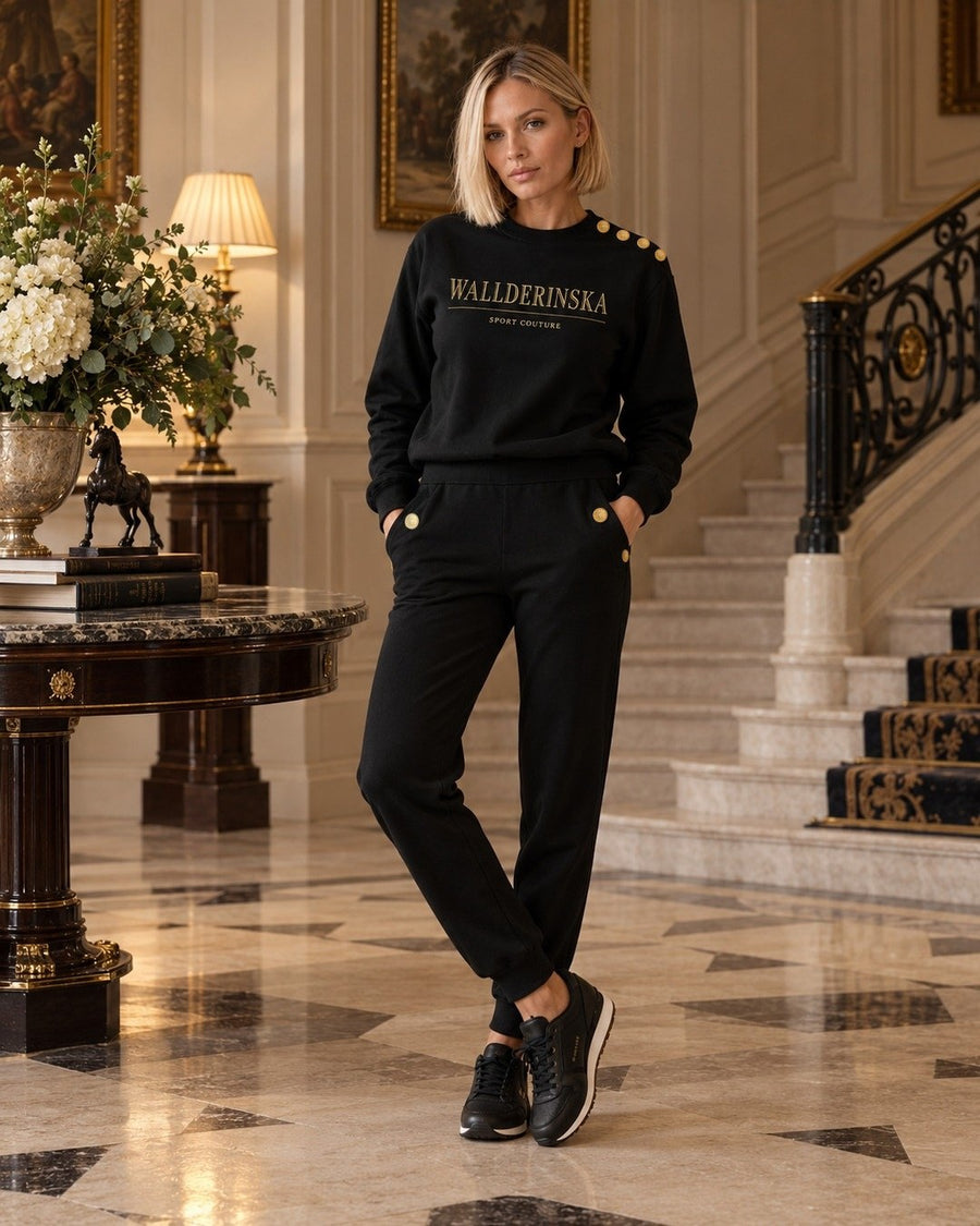 Edge Gold Button Pullover und Edge Gold Button Hose in einer Halle mit Marmorboden.