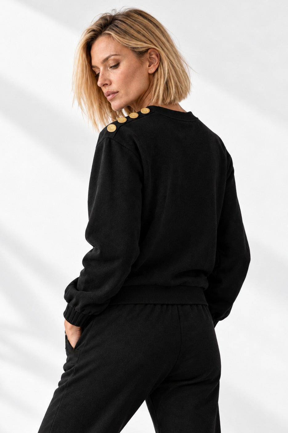 Edge Gold Button Sweater vista di tre quarti da dietro, con i bottoni dorati lungo la spalla.