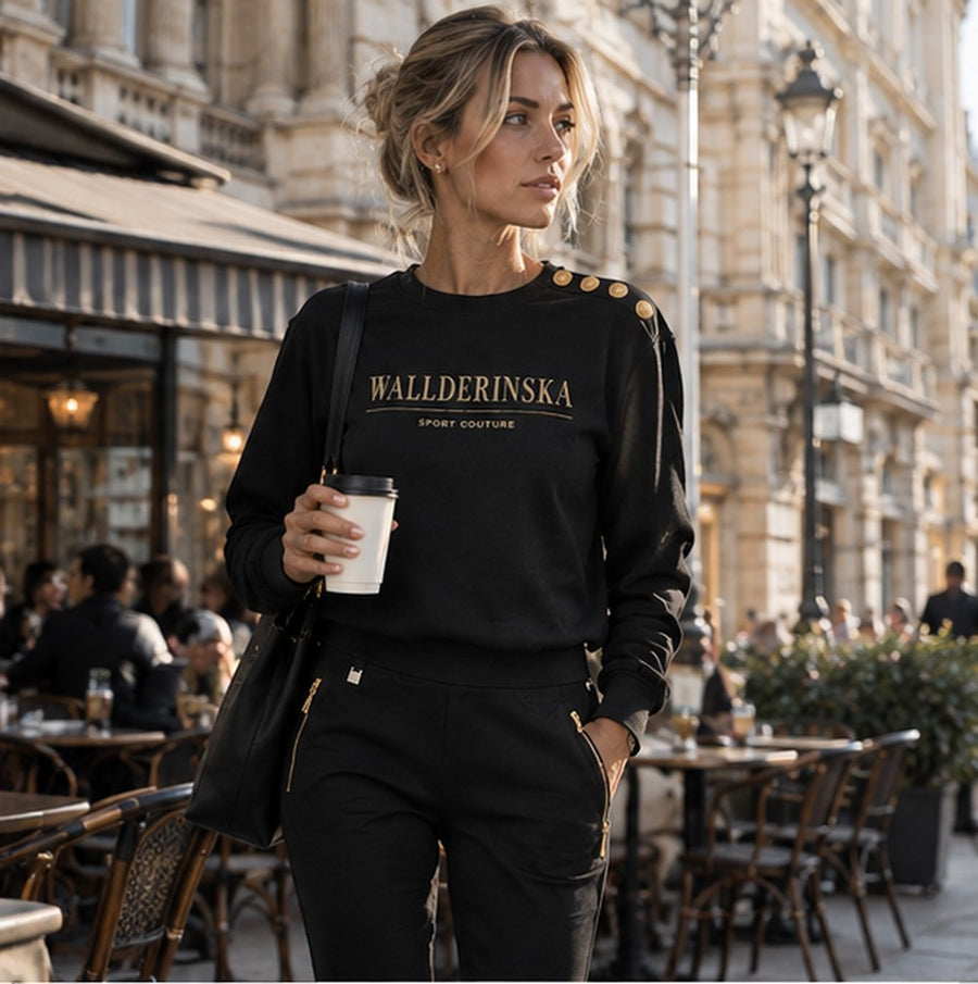 Edge Gold Button Pullover und Edge Casual Zip Hose mit Kaffee vor einem Café in der Stadt.